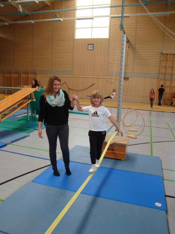Ein Kind balanciert mit Unterstützung auf der Slackline.